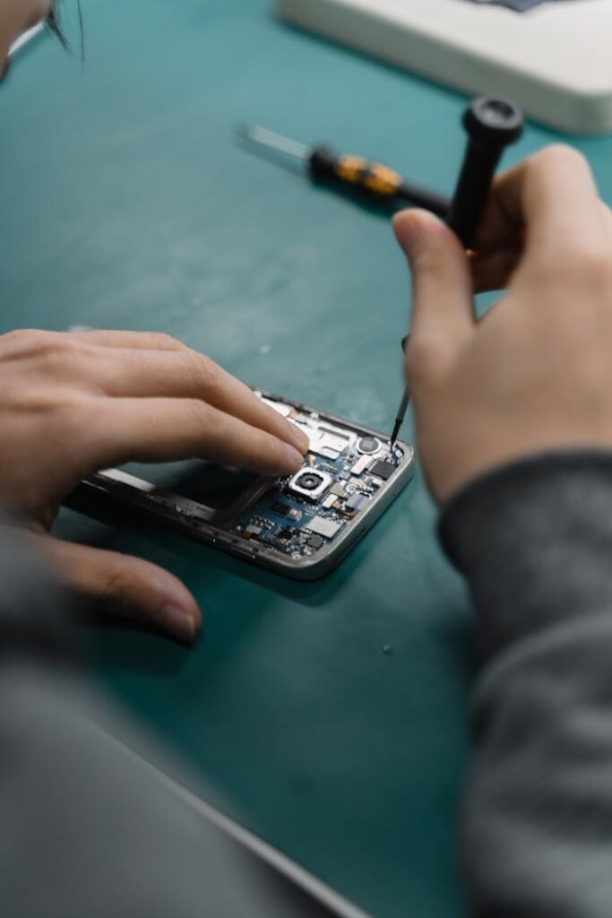 A focused view of repairing a smartphone circuit board with tools by hand.